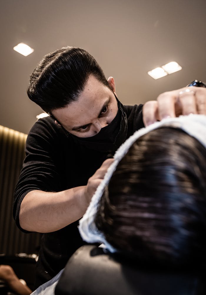 Barber in a Face Mask Cutting Mans Hair 